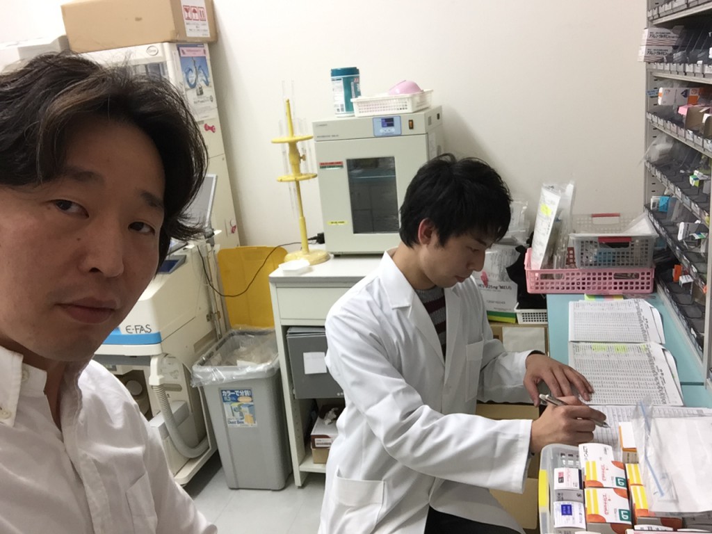 奥に写ってるのが新人薬剤師の崎田（さきた）君です。